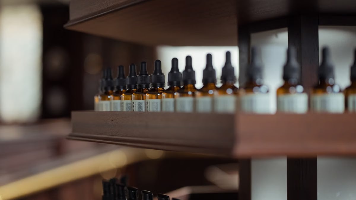 Close-up of essential oil bottle droppers on a wooden shelf in a store setting.